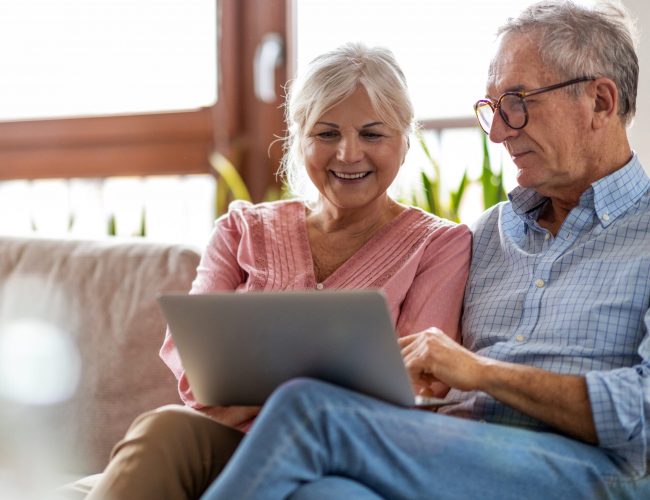 Mature couple using a laptop while relaxing at home